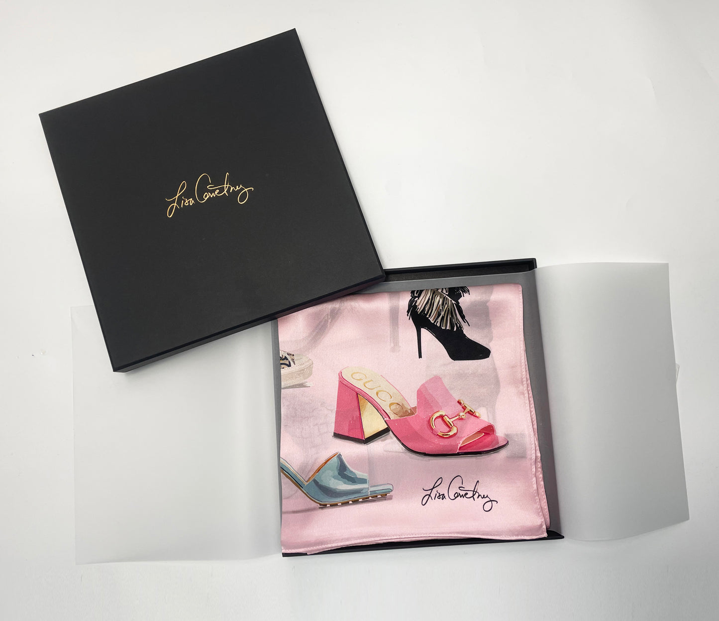 Image of the Designer Shoe Print scarf folded, wrapped in tissue inside a black box with Lisa Courtney logo in gold on top.