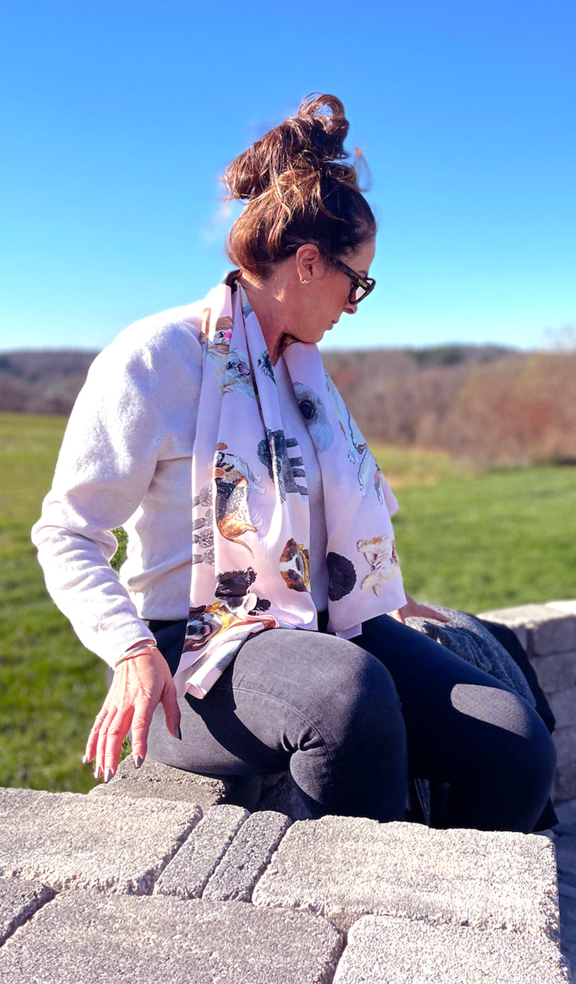 Image of a beautiful brunette woman with sunglasses on outside on terrace. She's wearing the Designer Dog Scarf draped around her neck and down her chest.