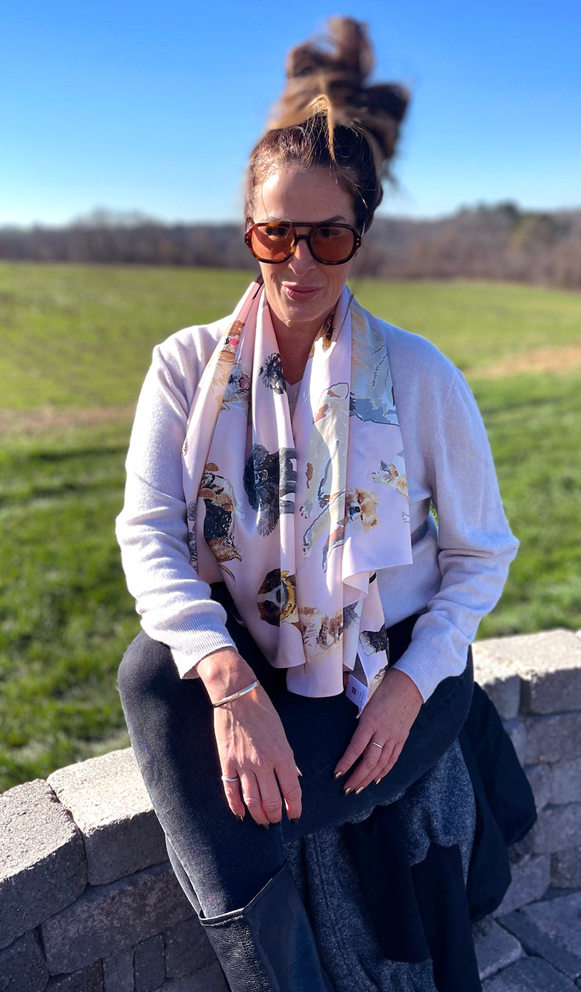 Image of a beautiful brunette woman with sunglasses on outside on terrace. She's wearing the Designer Dog Scarf draped around her neck and down her chest.